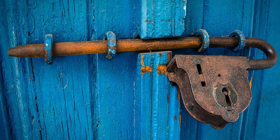 A an old rusted lock on a blue door
